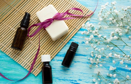 natural organic soap bottles essential oil and sea salt herbal bath  on a blue wooden table, Spa with flowersの写真素材