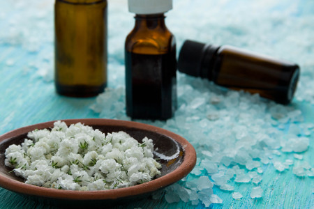 bottles essential oil and sea salt   on a blue wooden table, Spa with flowersの写真素材