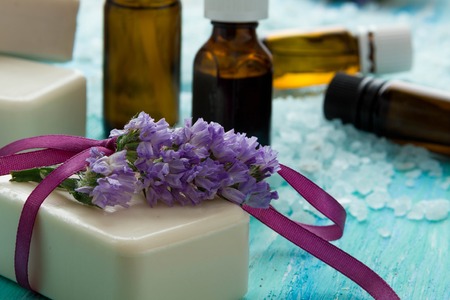 natural organic soap bottles essential oil and sea salt   on a blue wooden table, Spa with flowersの写真素材