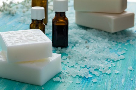 natural organic soap bottles essential oil and sea salt   on a blue wooden table, Spa with flowersの写真素材
