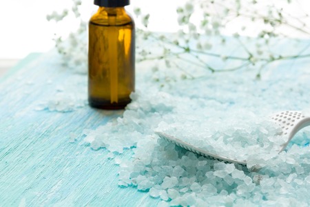 bottles essential oil and sea salt on a blue wooden table, Spa with flowersの写真素材