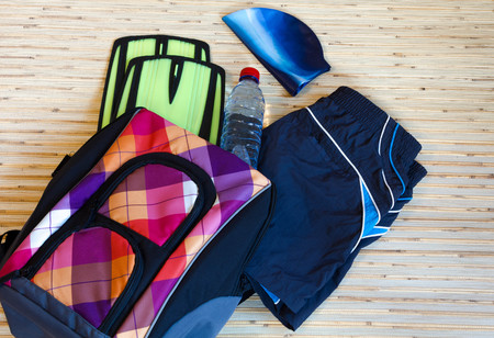 Collection of swimming equipment, flippers, cap, spilling out of the bag on the background for the school swim team background or competitive swim teams. The view from the top.の写真素材