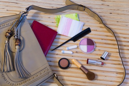 Things from the outdoor ladies handbag. women's purse on wood background. cosmetical shadows, varnishes, hygieneの写真素材