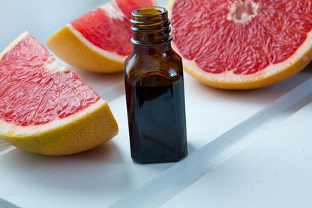 Essential oil in glass bottle with fresh, juicy grapefruit. Spa concept.  Selective focus.の写真素材