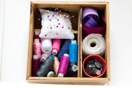 Vintage background with sewing accessories, tools, sewing kit. Scissors, bobbins with thread and needles on wooden white backgroundの写真素材