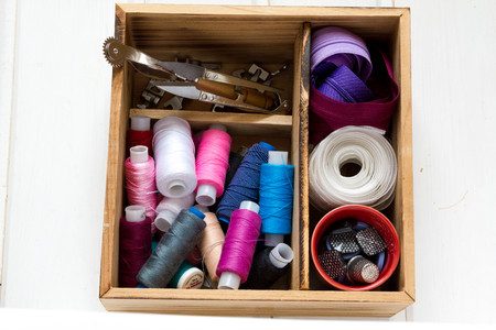 Vintage background with sewing accessories, tools, sewing kit. Scissors, bobbins with thread and needles on wooden white backgroundの写真素材