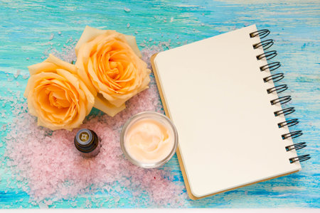 cosmetic products from rose, cream and a bottle of rose water, essential oil, flowers on turquoise wooden background, notebook, mockup, place for text,の写真素材