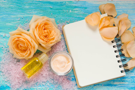 cosmetic products from rose, cream and a bottle of rose water, essential oil, flowers on turquoise wooden background, notebook, mockup, place for text,の写真素材