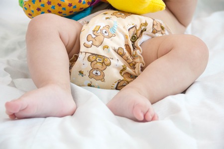baby in modern eco stacks of cloth diapers and replacement bushings selective focus close-up on bright backgroundの写真素材