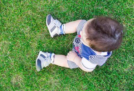 Happiness Baby boy sitting on the grass in the field. little nine month old baby sitting in the park...