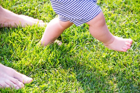 father and young son. Closeup of how the father supports the baby when he makes first steps. male hands holding small son's handsの写真素材