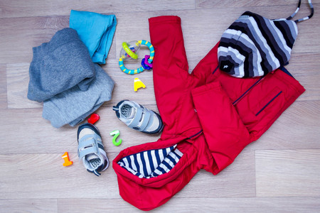 baby winter clothing, concept, autumn, sneakers, caps, toys. how to dress baby in winter. choose the shoes.の写真素材
