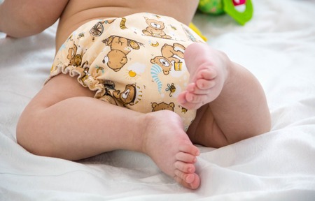 baby in modern eco stacks of cloth diapers and replacement bushings selective focus close-up bright background, little cute foot kid, the concept of health. hygiene of the child. reusable diapersの写真素材