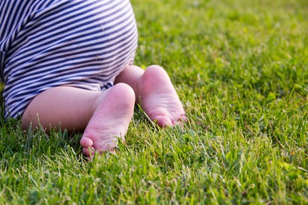 Child Feet Barefoot on Green Grass. Healthy Lifestyle. Spring Time. Rear view. the concept of flatfoot, the child is learning to crawl Close up.の写真素材