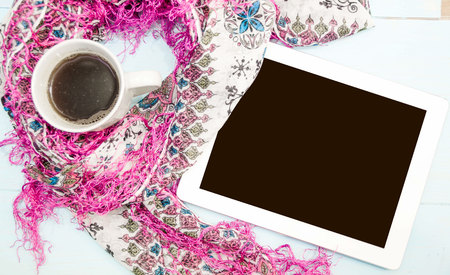 Cosy and soft winter background, knitted sweater and tablet and a Cup of hot coffee on an old vintage wooden board. Christmas holidays at home.の写真素材