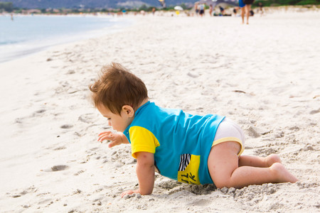 Little baby boy wearing blue rash guard suit playing on tropical ocean beach. UV and sun protection for young children. Toddler kid during family sea vacation Summer water fun.の写真素材