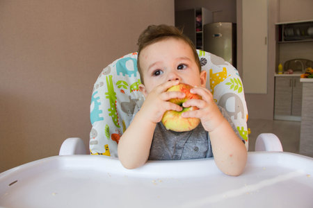 Adorable Indian baby boy eating apple over white background