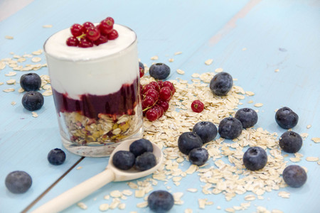 Yogurt with granola fresh blueberries, in glass bowl over old wood background. Vintage effect.の写真素材