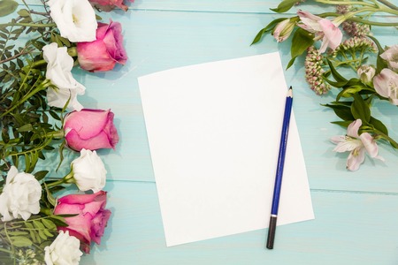 Row of roses on wooden background with space for message. Mothers Day background. empty paper sheet on turquoise rustic table from above, beautiful vintage card, top view, flat layの写真素材