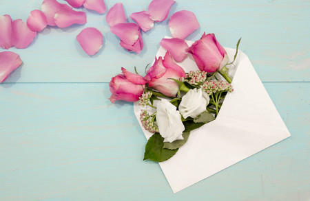 Beautiful roses and petals in the envelope on the worn wooden table, the concept of love messages for women, greeting cardの写真素材