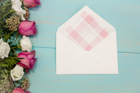 scattered flowers rose and white envelope on turquoise rustic table from above, beautiful vintage card, top view, copy space for text, flat layの写真素材