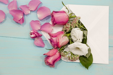 Beautiful roses and petals in the envelope on the worn wooden table, the concept love messages for women, greeting cardの写真素材