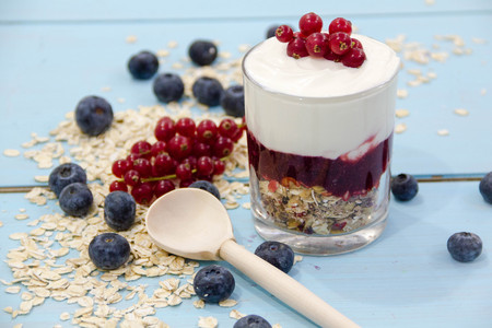 Yogurt with granola and fresh blueberries, in glass bowl over old wood background. Vintage effect.の写真素材