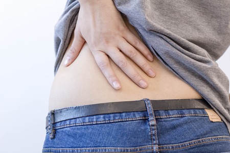 Attractive female person suffers from backache. All on white background. young woman with backache. injury woman stretches back pain backache, spinal . cause of Long working hours and health.の写真素材