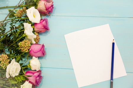 Bouquet of flowers rose and empty paper sheet on turquoise rustic table from above, beautiful vintage card, top view, copy space for textの写真素材