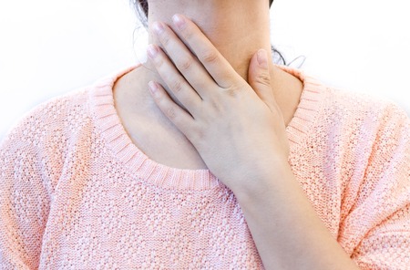 woman with throat pain, thyroid gland control. female touches her neck, white background.の写真素材