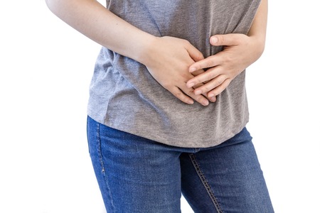 Young woman with stomach issues. woman white sport shirt stomachache hand at abdomen. menstruation pain or stomach ache, hand holding belly closeupの写真素材