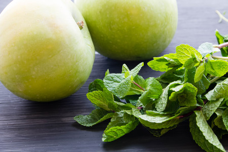 Green apples with mint leaves on wooden table.の写真素材