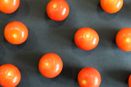 Fresh cherry tomatoes on black background. Top view with copy space.