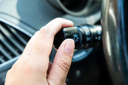 womans hand switches on the headlights in the car
