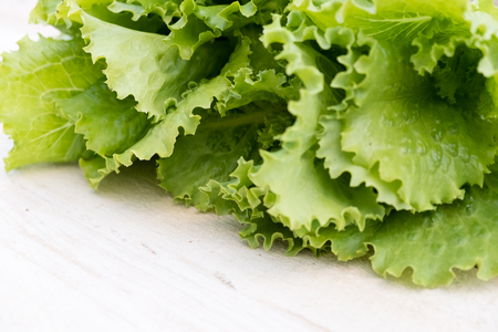 Green lettuce leaves. Lettuce leaves on wooden background. Fresh lettuce on kitchen table. Healthy organic food.の写真素材