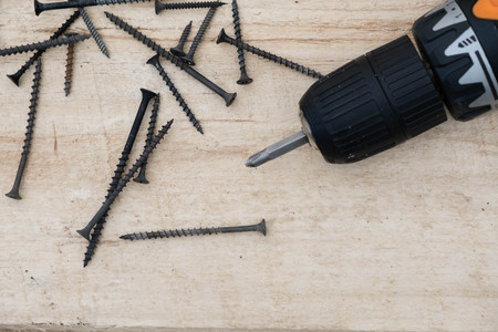 Many screws and a screwdriver on a pine board. Cordless drill with screws DIY backgroundの写真素材