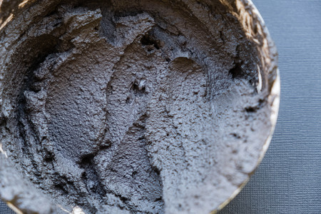 Black volcanic cosmetic clay in a bowl. cosmetic clay texture close up. solution cosmetic clay abstract backgroundの写真素材