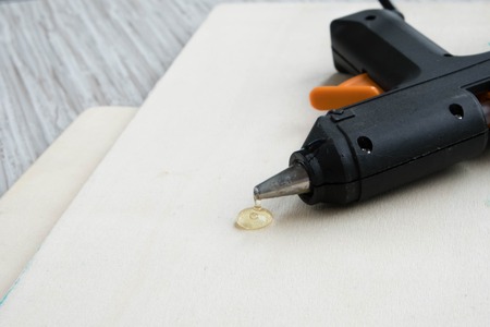 Electric hot glue gun on wood background. the concept of repair or creativity backgroundの写真素材