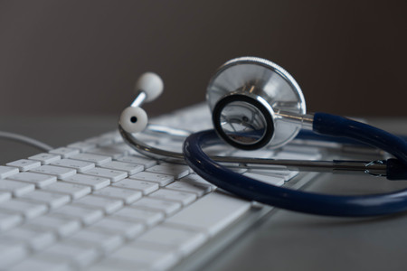 Silver stethoscope lying down on an laptop, toned blue.の写真素材
