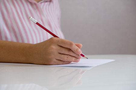 Closeup of woman's hand writing on paper. Close up of lady's hand writing in notepad placed on...
