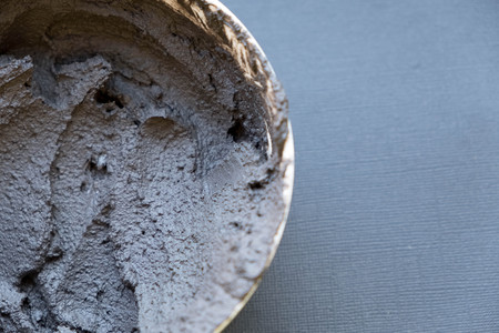 Black volcanic cosmetic clay in a bowl. cosmetic clay texture close up. solution cosmetic clay abstract backgroundの写真素材