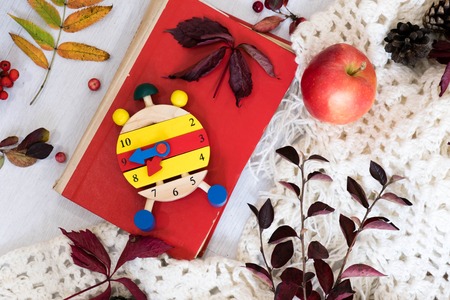 heart clock with glasses and mobile phone on red book ,education concept, mobile phone with headphones, autumn leaf on a vintage table surface, selective focusの写真素材