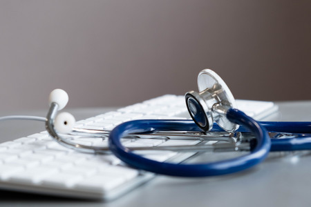 Silver stethoscope lying down on an laptop, toned blue.の写真素材