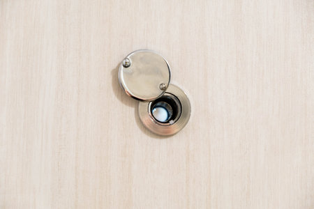 close up door eye lens peephole on white gray wooden texture backgroundの写真素材