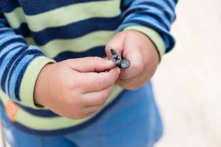Boy playing with nails on a tableの写真素材