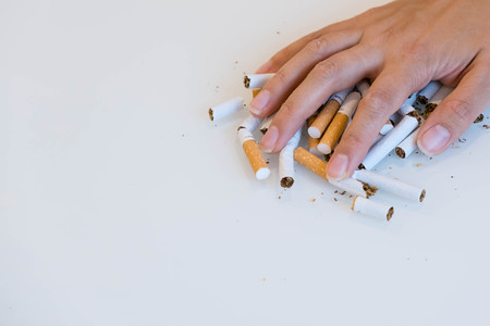 Stop smoking. Close up of male hand breaking cigarettes with his fist. Isolated and copy space in left sideの写真素材