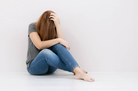 sad woman hug her knee and cry. The depression woman sit on the floor. Teenager girl with depression sitting alone on the floor in the dark room. Toned photoの写真素材