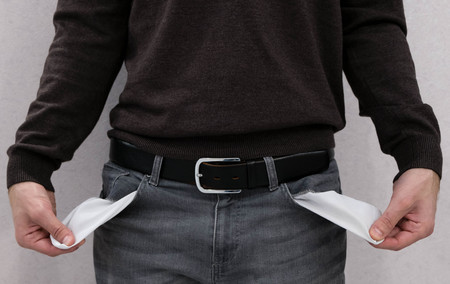 Financial difficulties, bad economy, no money concept. Young man student boy showing empty pockets, part of body male hips wearing jeans pants. stressed young man poor gesture. Empty pocketの写真素材