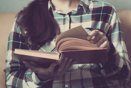 Vintage tone of Asia woman reading book in library .Retro filter effect,soft focus,low light selective focusの写真素材
