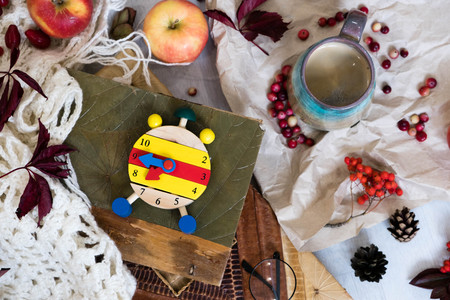 Fall Time Alarm clock on a rustic wooden table with colorful Autumn leaves. with light shadow and shallow depth of field. Daylight savings time concept. Autumn Time Change, with copy space. Top viewの写真素材